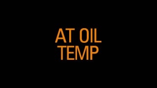 Icône orange de témoin d’alerte de la température de l’huile de transmission sur boîte automatique avec texte « AT OIL TEMP » sur fond noir.