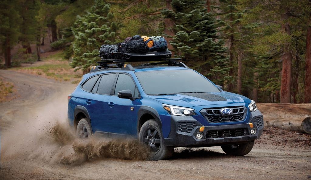 Vue 3/4 avant du Subaru Outback 2025 performant sur une terre en forêt.