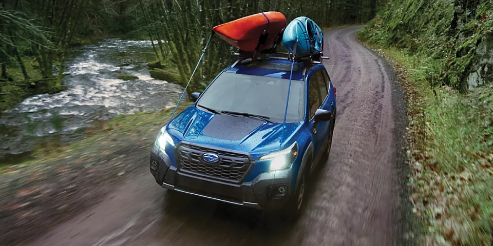 Vue 3/4 avant du Subaru Forester 2024 sur route en forêt