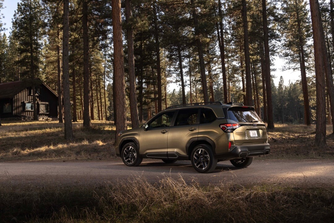 Vue 3/4 arrière du Subaru Forester 2025 garé sur un chemin en forêt.