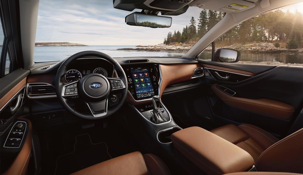 Intérieur du Subaru Outback Wilderness 2025 avec tableau de bord et sièges brun chocolat, stationné au bord d’un lac.